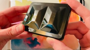 My hands holding the shiny black bijou with colorful watercolor paper in the background 