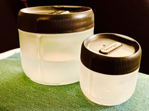 Humangear larger water container to the right of the little 1oz one, with a black background 