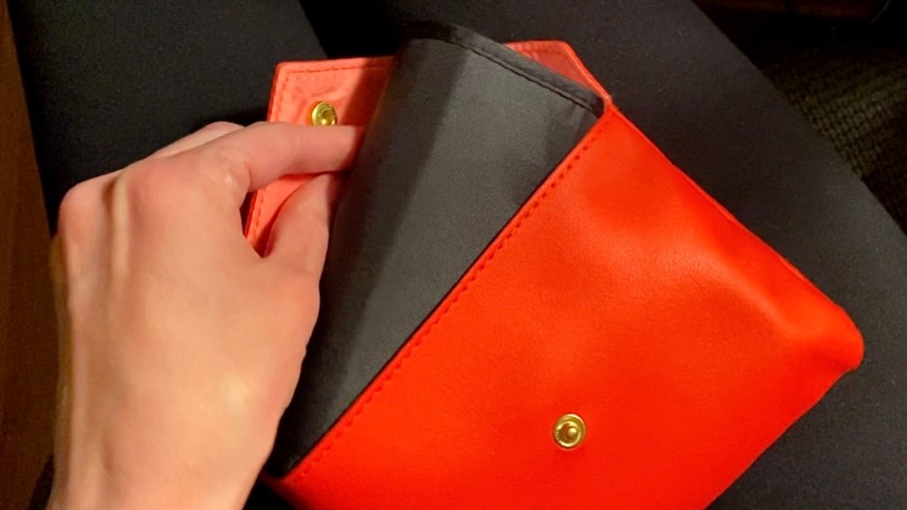 My hand putting the qardioarm blood pressure cuff into an ipsy makeup bag. 
