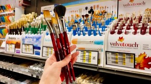 My hand holding Princeton velvetouch brushes 3/4 flat, some rounds, and a mop brush in Blick Art Materials in DC