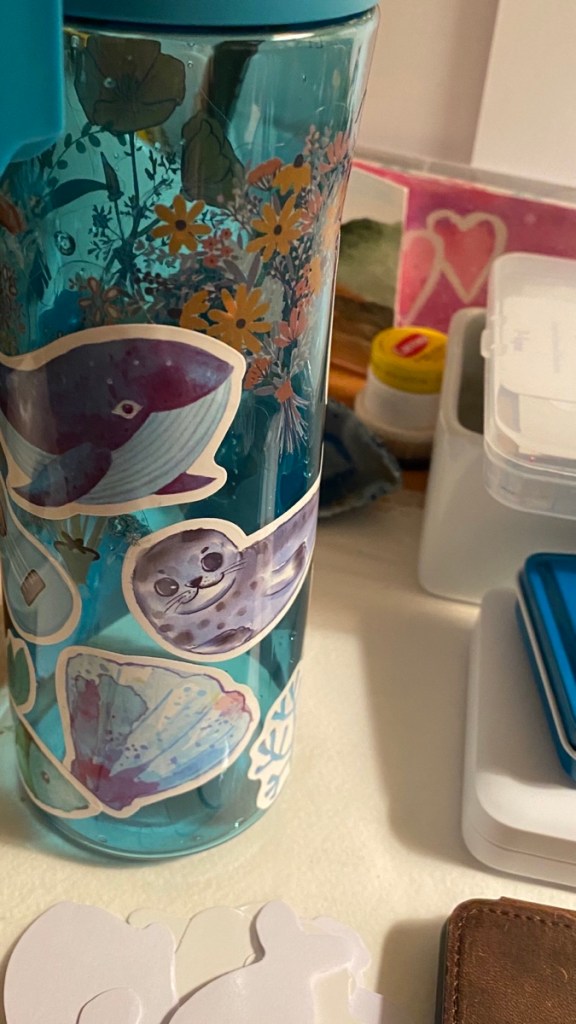 My water bottle on the desk with stickers on it 